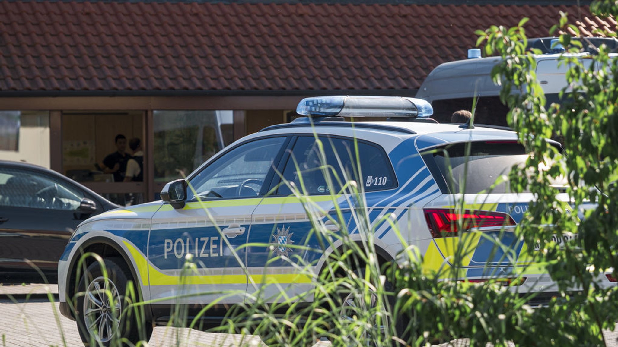 Ein Polizeifahrzeug steht auf dem Gelände des regionalen Netzbetreibers Überlandwerk Rhön. Ein 21-Jähriger hat in der Firma eine Kollegin getötet und zwei weitere Mitarbeiter schwer verletzt.