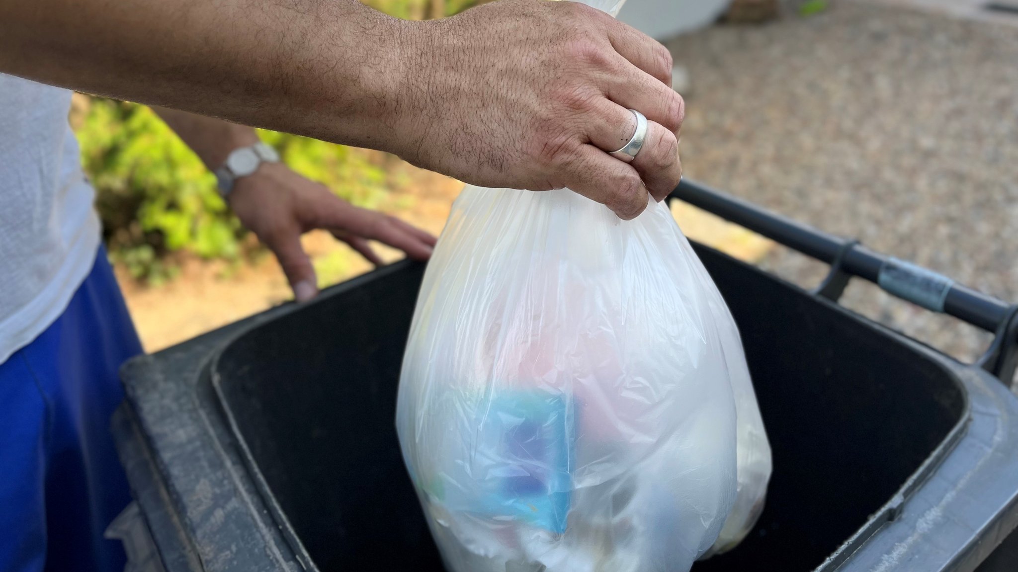 Ein Mann wirft einen Müllsack in eine Tonne.